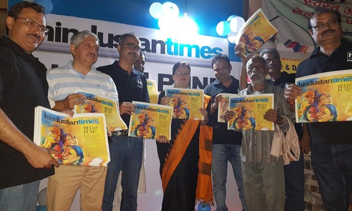 Group photo of executives and guests holding Hindustan Times "Hello Pune" special-edition newspaper covers at an indoor launch event, HT logo on backdrop.