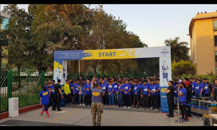 Crowd of participants in blue "Walkathon" t-shirts gathered at a start-line banner reading "START" with Allstate branding.
